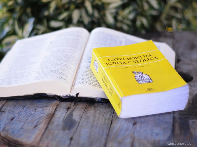 Bíblia aberta e Catecismo sobre mesa de madeira